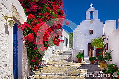 Traditional colorful mediterranean street with flowers and church, Cyclades, Greece Stock Photo