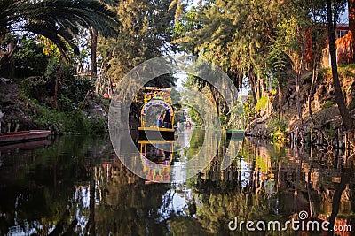 Traditional colorful trajinera surrounded by trees in Xochimilco lake Editorial Stock Photo