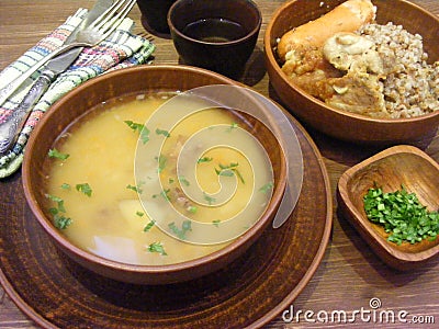 Traditional rustic cuisine of Belarus, russian cuisine: fresh soup and buckwheat in clay dishes on wooden table Stock Photo