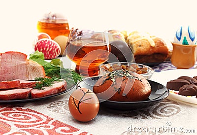 Traditional easter dinner set with sliced meat, bread with herbs, handmade colored eggs, chocolates, easter cake and glasses of ju Stock Photo