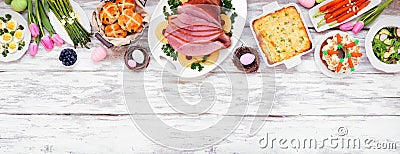 Traditional Easter ham dinner. Overhead view top border on a white wood banner background with copy space. Stock Photo