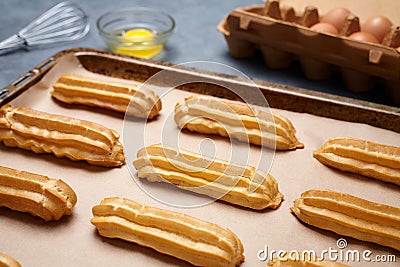 Traditional eclairs or profiterole preparing with eggs on baking sheet Stock Photo