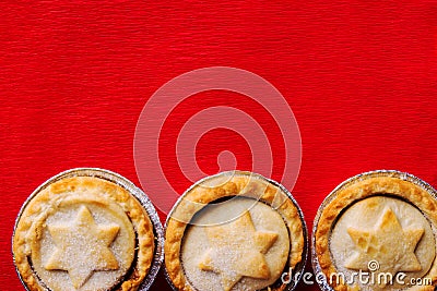 Traditional English Christmas dessert pastry mince pies in muffin tins sprinkled with sugar on crimson red table cloth Stock Photo