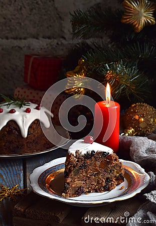 Traditional english Christmas steamed pudding with winter berries, dried fruits, nut in festive setting with Xmas tree and burning Stock Photo