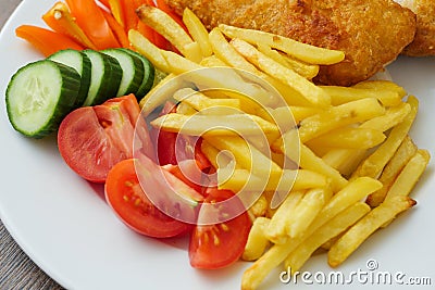 Traditional english dish with battered white cod, french fries and fresh vegetable served on a white plate. Close up Stock Photo