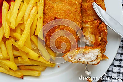 Traditional english dish with battered white cod, french fries and fresh vegetable served on a white plate. Close up. Small piece Stock Photo