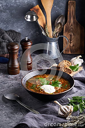 Traditional European and Russian soup borsch with cabbage, sour cream and meat served in a plate on a dark stone table Vertical Stock Photo