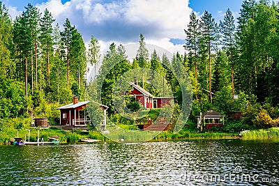 A traditional Finnish wooden cottage with a sauna and a barn on the lake shore. Summer rural Finland. Stock Photo