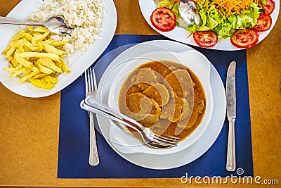 Traditional food from Alentejo - cow`s tongue in a sauce served with salad, rice and french fries, Portugal Stock Photo