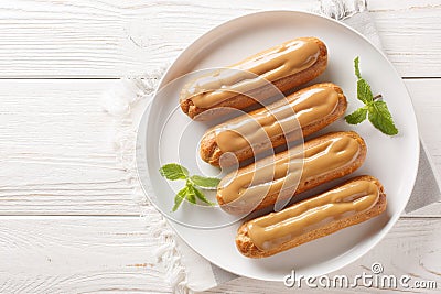 Traditional French dessert Eclairs with custard and topped with caramels icing close-up in a plate. Horizontal top view Stock Photo