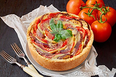 Traditional French dish quiche - pie with eggplants and tomatoes. Homemade vegetable tart on the black wooden background Stock Photo