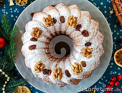 Traditional fruitcake for Christmas decorated with powdered sugar and nuts, raisins. Delicioius Homemade Pastry. New year Stock Photo