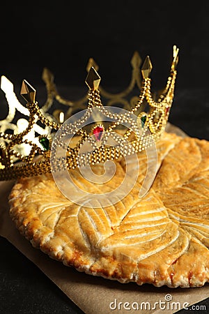Traditional galette des Rois with decorative crown on black table, closeup Stock Photo