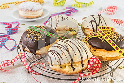 Traditional german Berliner pastries glazed with dark and white chocolate and hazelnut brittle, decorated for party or carnival Stock Photo