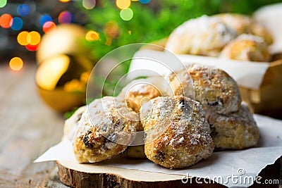 Traditional German Christmas pastry mini stollen on parchment paper on plank wood table. Fresh green juniper branch golden balls Stock Photo