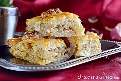 Traditional Greek baklava made with filo dough, sugar syrup and wallnuts on a metal tray with metal coffee cup on a Stock Photo