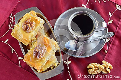 Traditional Greek baklava made with filo dough, sugar syrup and wallnuts on a metal tray with metal coffee cup on a Stock Photo