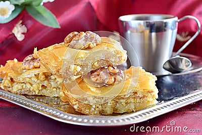Traditional Greek baklava made with filo dough, sugar syrup and wallnuts on a metal tray with metal coffee cup on a Stock Photo