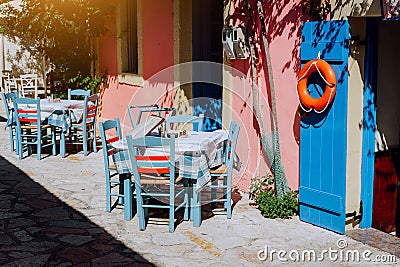 Traditional greek vivid lilac colored tavern on the narrow Mediterranean street on hot summer day Stock Photo
