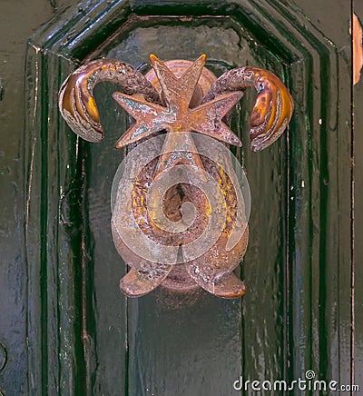 Traditional handle and doorknocker made of brass in the form of a dolphin on the doors of old houses in Malta Stock Photo