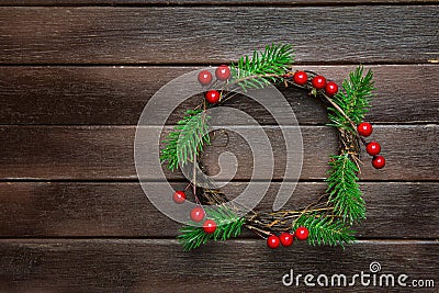 Traditional Handmade Christmas Wreath Green Fir Tree Branches Twigs Holly Berries on Dark Plank Wood Background. Top View Stock Photo