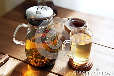 Traditional heral tea with glass teapot, cup, dried rose buds. Flowers on wooden table at home,sunlight background Stock Photo