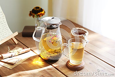 Traditional heral tea with glass teapot, cup, dried rose buds. Flowers on wooden table at home,sunlight background Stock Photo