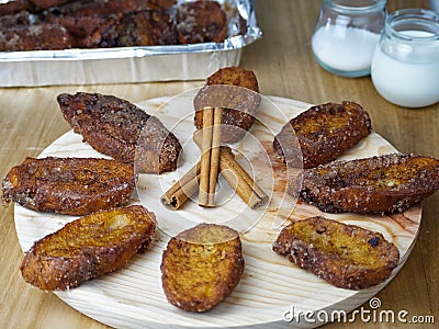 Traditional homemade and Delicious Spanish Torrijas making a circle and three cinnamon sticks in the middle on a round wooden Stock Photo