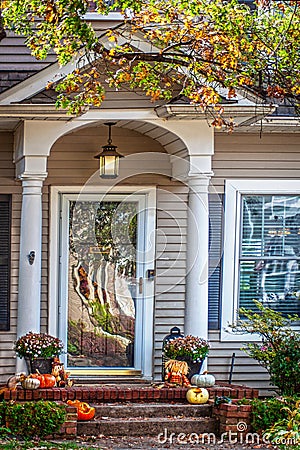 Traditional house with porch decorated for fall with partly eaten pumpkins and a squirrel eating another one - distorted Stock Photo