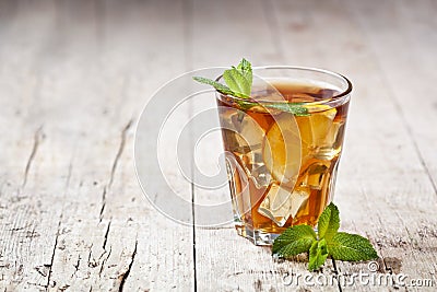 Traditional iced tea with lemon, mint leaves and ice in glass on rustic wooden table background Stock Photo