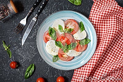 Traditional Italian Caprese Salad - sliced tomatoes, mozzarella cheese and basil on stone background, top view. Stock Photo