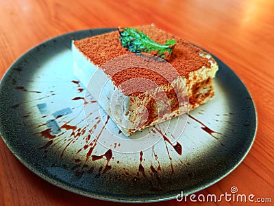Traditional Italian dessert called tiramisu, with cacao powder and mint leaf on top. Close up shot from top side Stock Photo