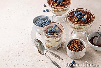 Traditional Italian dessert tiramisu with blueberries in glass. Individual trifle. Homemade layered cake with berries in cup. Stock Photo