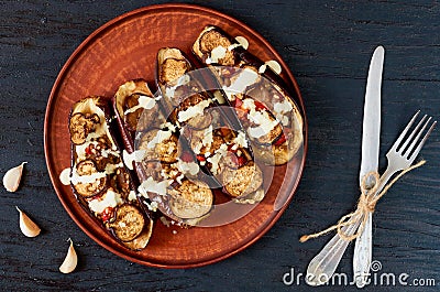 Traditional Italian dish - grilled eggplants stuffed with rise, tomatoes, garlic and sauce on a vintage plate Stock Photo