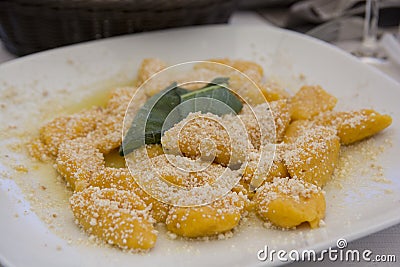 A traditional Italian dish: Pumpkin Gnocchi with Parmesan cheese and a decorative sage leaf Stock Photo
