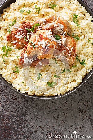 Traditional Italian dish Risotto with chicken, garlic, parmesan cheese and herbs closeup on the plate. Vertical top view Stock Photo