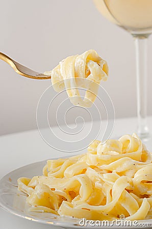 Traditional Italian pasta - Fetuccini Alfredo on a white table with golden appliances Stock Photo