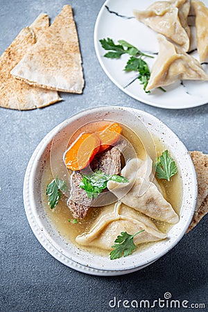 Traditional Jewish Kreplach soup with meat and carrot, gray background Stock Photo