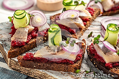 Traditional matie herring with beetroot salad, fresh cucumber and onion rings on the toasts. Scandinavian cuisine Stock Photo