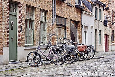 Traditional medieval town. Narrow paved street with old brick houses and bikes near entrance Stock Photo