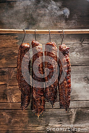 Traditional method of smoking meat in smoke. Smoked ham, bacon, pork neck and sausages in a smokehouse Stock Photo