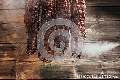 Traditional method of smoking meat in smoke. Smoked ham, bacon, pork neck and sausages in a smokehouse Stock Photo