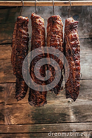 Traditional method of smoking meat in smoke. Smoked ham, bacon, pork neck and sausages in a smokehouse Stock Photo