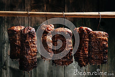 Traditional method of smoking meat in smoke. Smoked ham, bacon, pork neck and sausages in a smokehouse Stock Photo