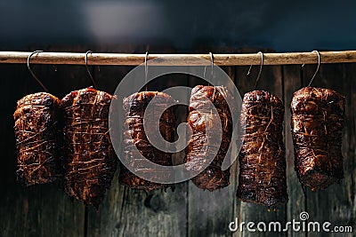 Traditional method of smoking meat in smoke. Smoked ham, bacon, pork neck and sausages in a smokehouse Stock Photo