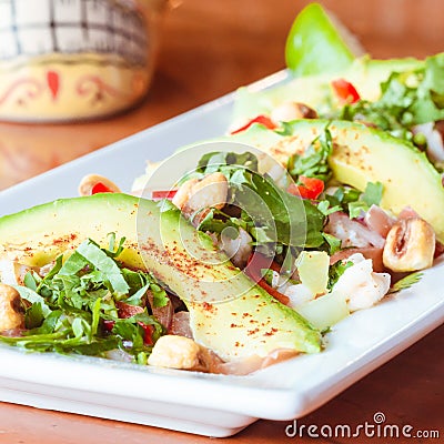 Traditional mexican avocado ceviche platter on light shiny wood surface in mexican restaurant with traditional mexican hibiscus Stock Photo