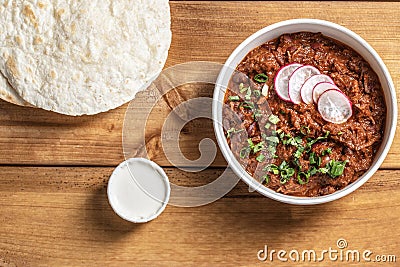 Traditional Mexican dish chilli con carne with minced meat, red beans, herbs and tortilla in paper dish Stock Photo