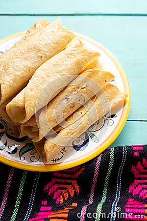 Mexican potato and cheese fried tacos also called flautas on turquoise background Stock Photo