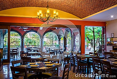 Traditional mexican restaurant interior with chairs and tables, chandelier and brick ceiling Stock Photo