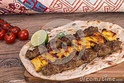 Traditional Middle eastern Persian chicken and lamb meat Shashlik Kebab skewered meat BBQ Grill on flat pita bread and saffron r Stock Photo